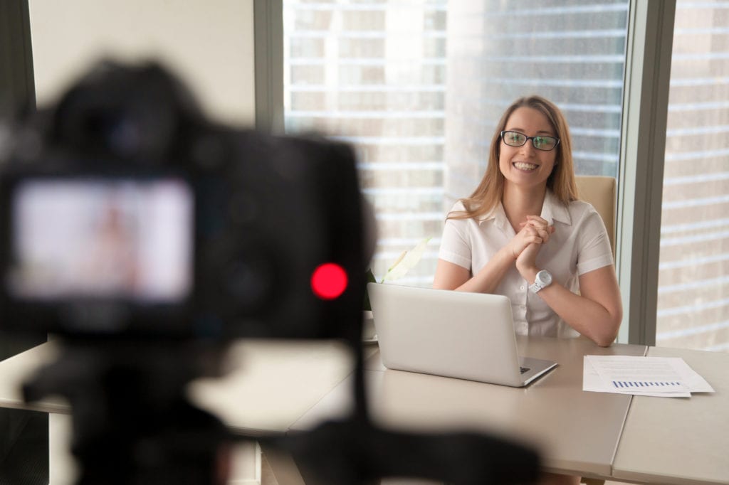 Smiling businesswoman talking on camera, lady recording business video blog