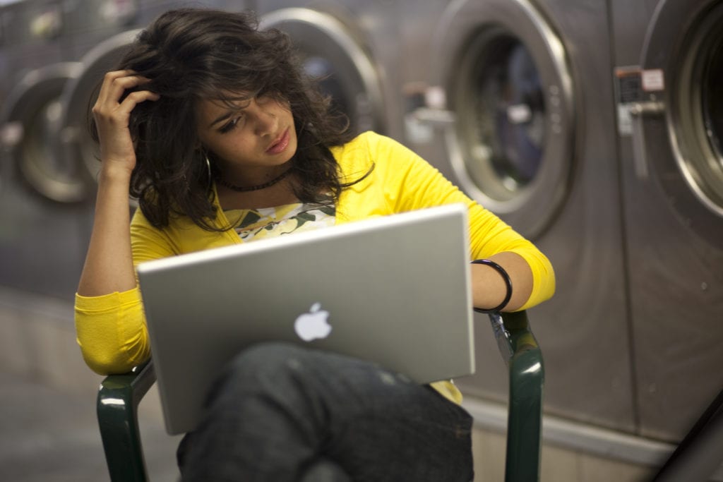 Girl working on laptop at laundrymat