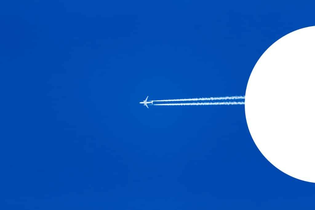 Commercial jet in the sky with two distinct contrails behind it.
