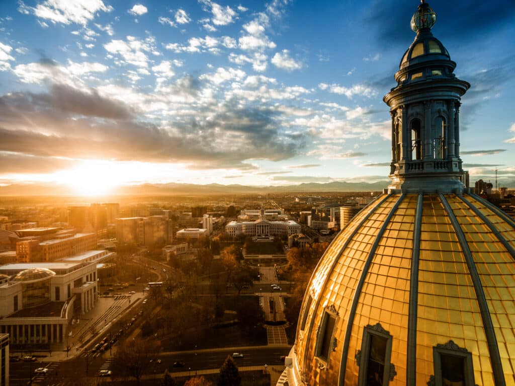 Aerial/Drone photograph of a sunset over the Colorado state capital building. Capital city of Denver. The Rocky Mountains can be seen on the horizon