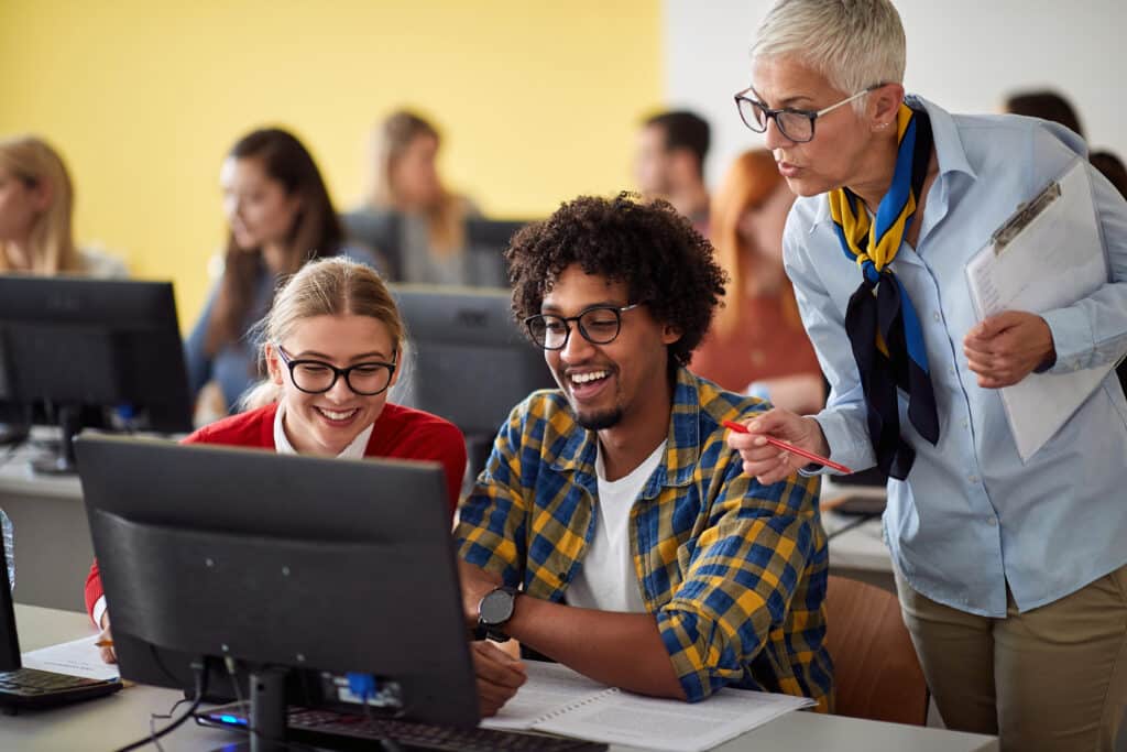 Teacher looking pupils task on theirs computer