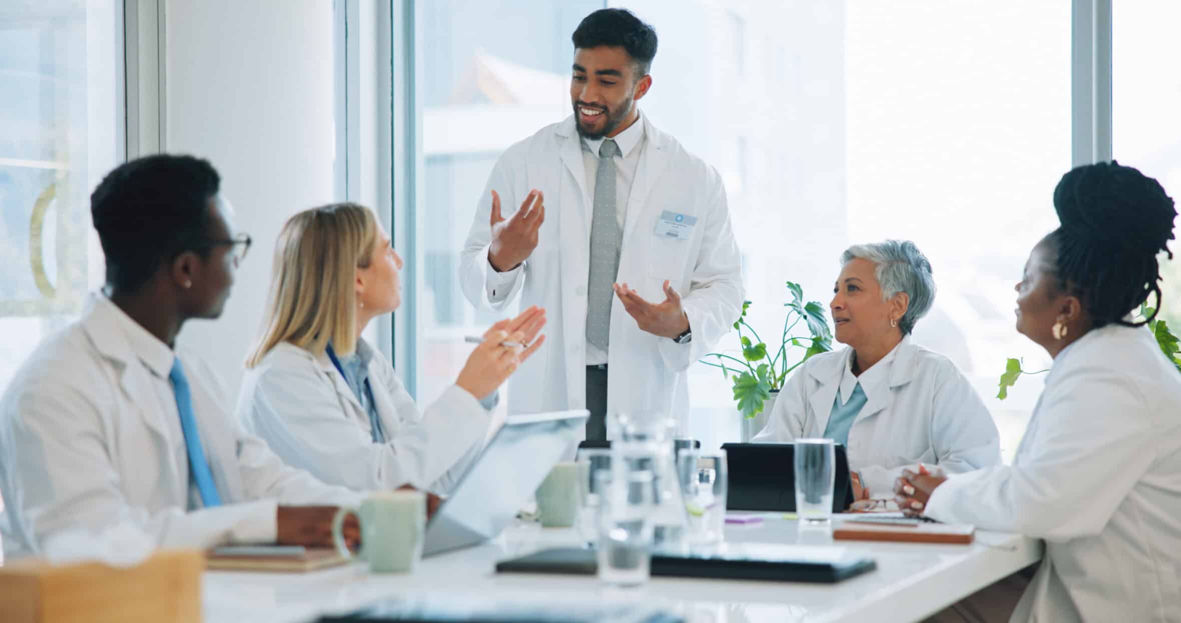 an, doctor and team in meeting for healthcare, planning or strategy together at hospital or office. Group of medical employees in teamwork, discussion or collaboration for presentation at clinic