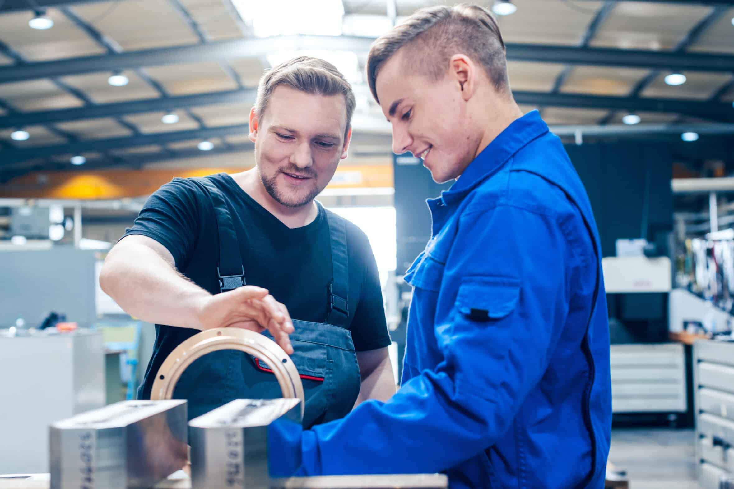 Skillful master discussing a workpiece with his apprentice or trainee