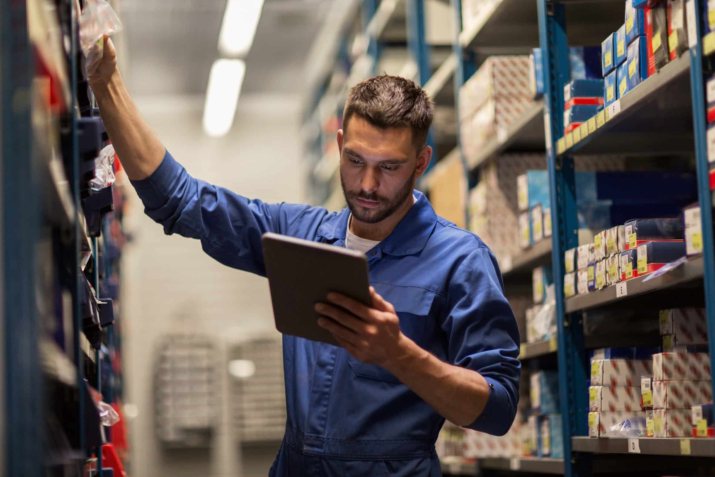 car service, repair, maintenance and people concept - auto mechanic man or smith with tablet pc computer looking for spares at workshop or warehouse