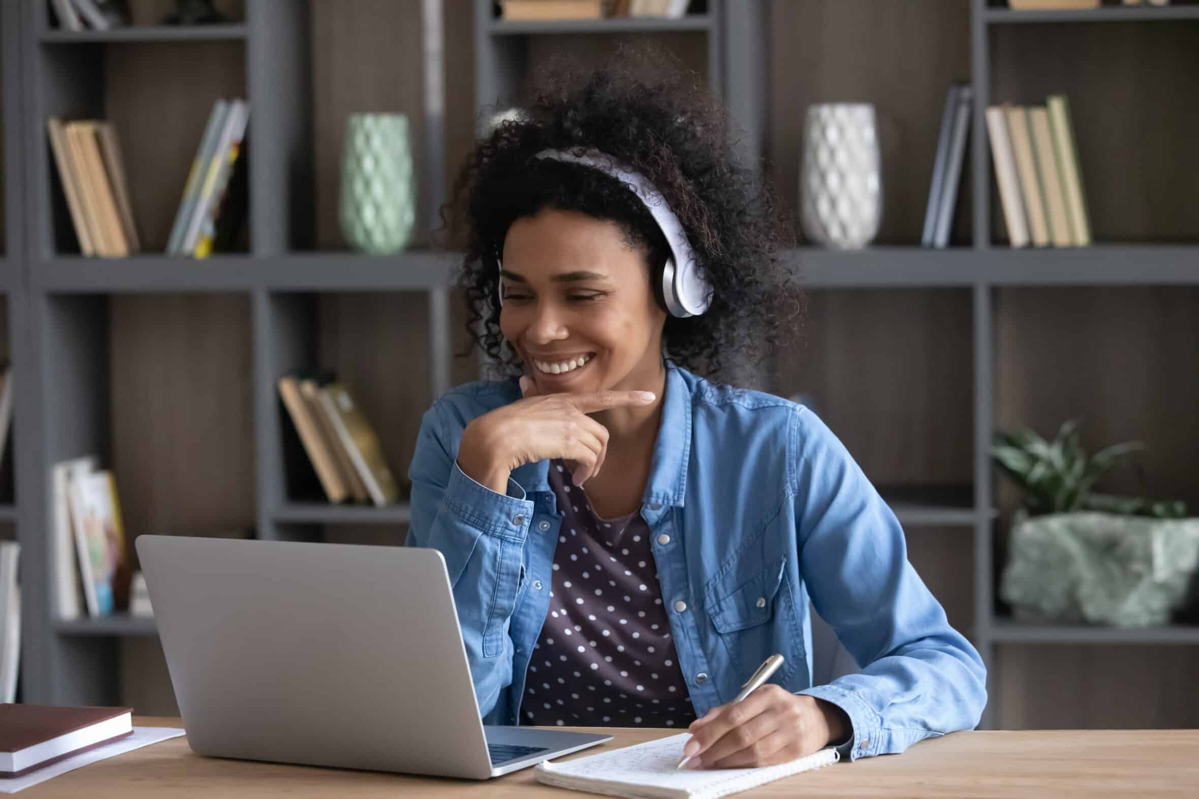 Happy student girl in wireless headphones making video call
