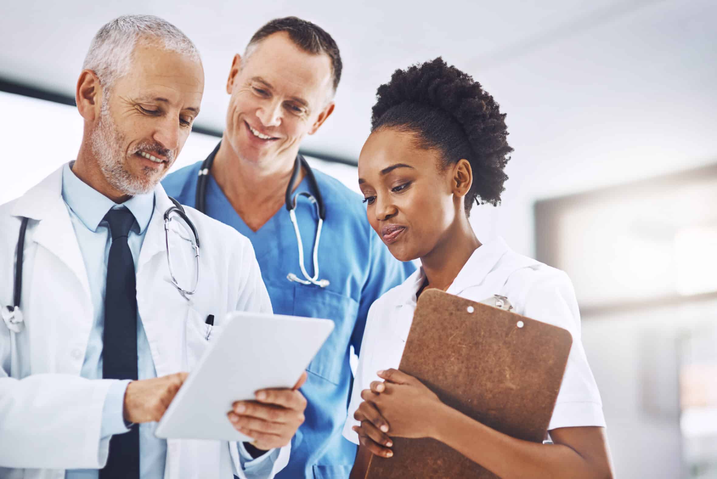 Senior doctor, tablet and coaching team in healthcare for research, teamwork or meeting at hospital. Happy elderly medical professional training staff on technology in group collaboration at a clinic