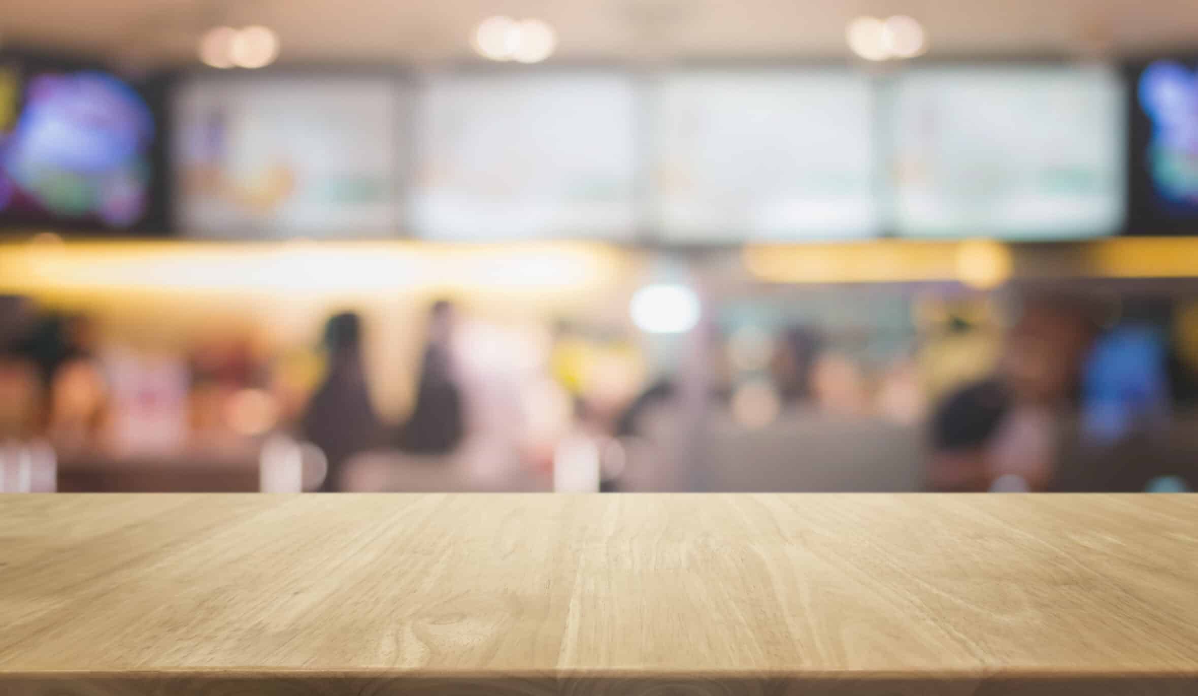 Wood table top and blurred restaurant kitchen interior background - can used for display or montage your products.
