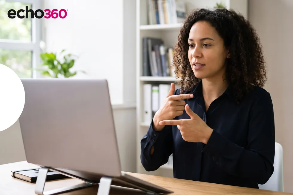 Woman doing ASL signs in front of laptop